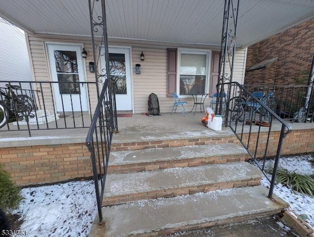 snow covered property entrance with a porch