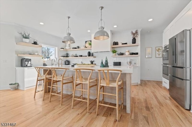 bar with appliances with stainless steel finishes, white cabinetry, decorative backsplash, decorative light fixtures, and light wood-type flooring