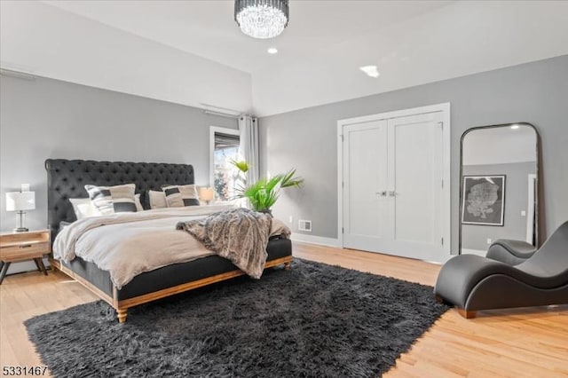 bedroom with an inviting chandelier, wood-type flooring, and a closet