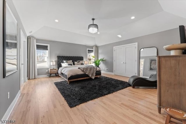 bedroom with a raised ceiling and light wood-type flooring