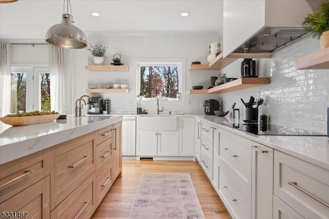 kitchen featuring white cabinetry, sink, decorative backsplash, hanging light fixtures, and light stone counters