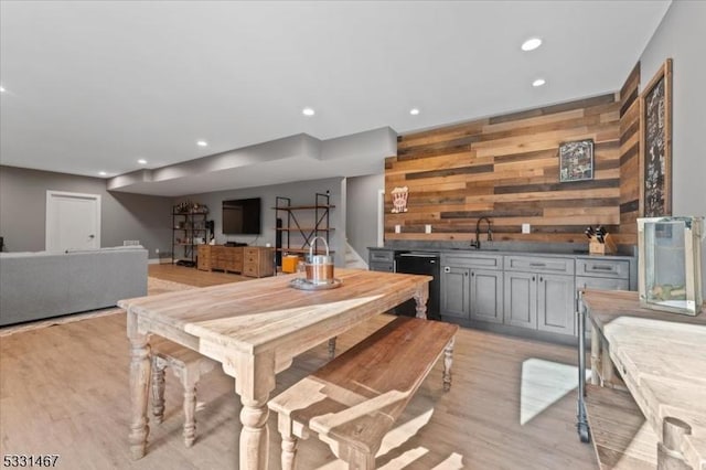 dining area with wet bar, light hardwood / wood-style floors, and wood walls