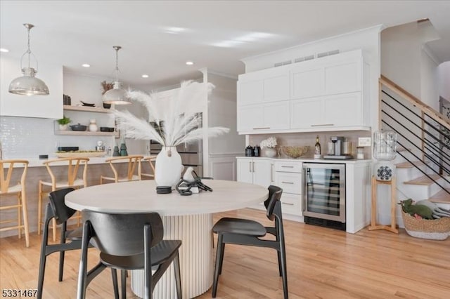 kitchen featuring white cabinetry, light hardwood / wood-style floors, decorative backsplash, decorative light fixtures, and beverage cooler