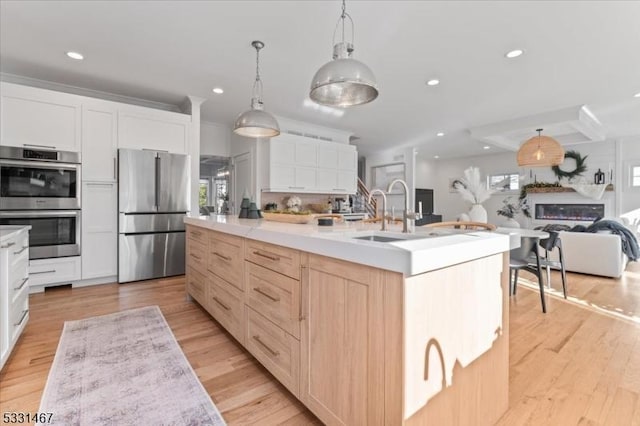 kitchen featuring sink, decorative light fixtures, light brown cabinets, an island with sink, and stainless steel appliances