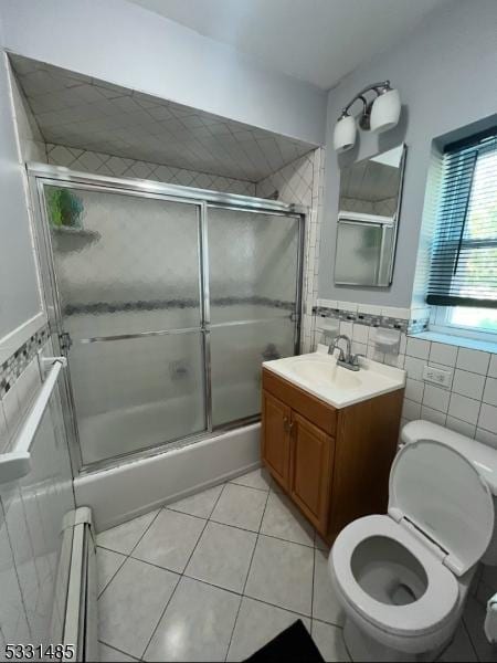 full bathroom with enclosed tub / shower combo, tile patterned floors, toilet, vanity, and tile walls