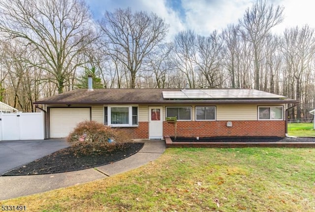 ranch-style home with solar panels, a garage, and a front yard