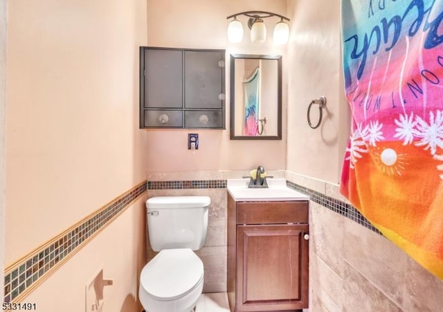 bathroom featuring vanity, toilet, and tile walls