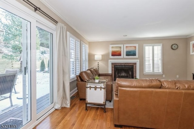 living room with light hardwood / wood-style flooring, a brick fireplace, and crown molding