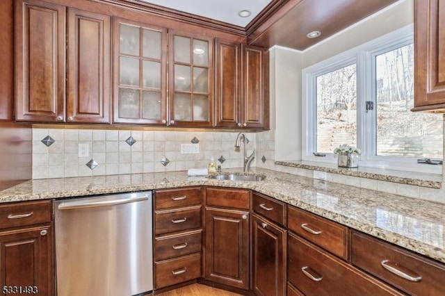 kitchen with stainless steel dishwasher, backsplash, light stone countertops, and sink