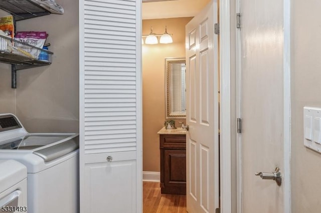 laundry area with light hardwood / wood-style floors and washer and clothes dryer