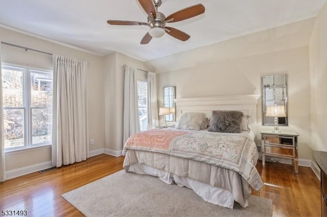 bedroom with multiple windows, ceiling fan, and wood-type flooring