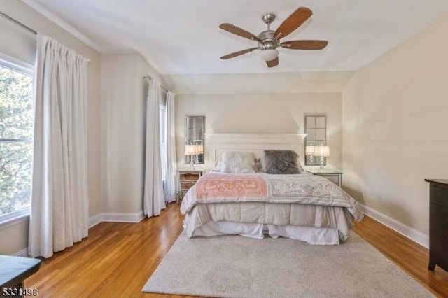 bedroom featuring ceiling fan, light wood-type flooring, and multiple windows