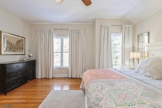 bedroom with ceiling fan, light hardwood / wood-style floors, and multiple windows