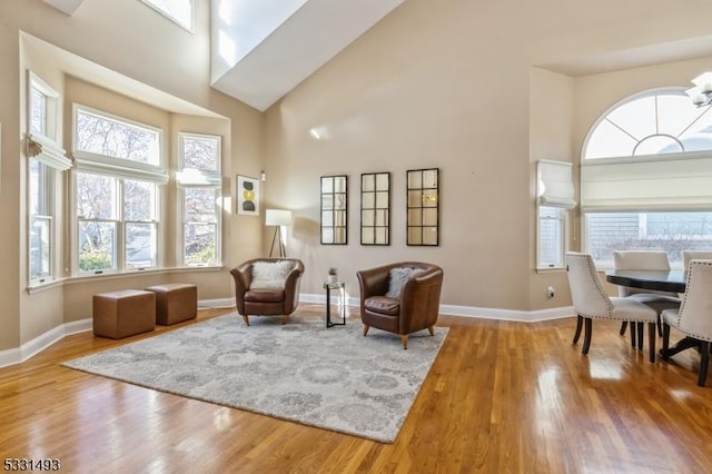 sitting room featuring a towering ceiling and wood-type flooring