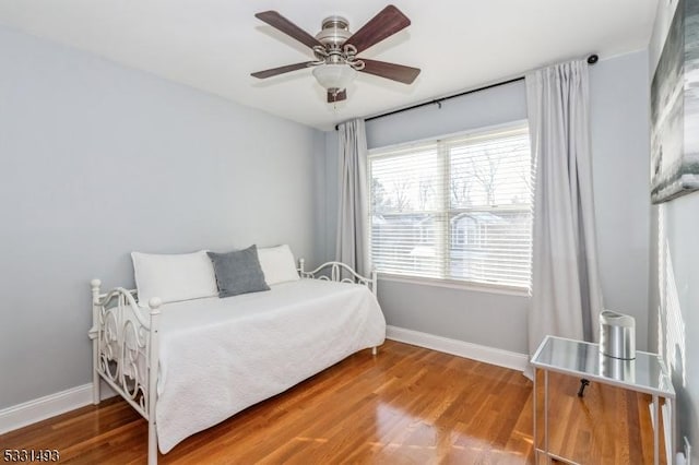 bedroom with ceiling fan, wood-type flooring, and multiple windows