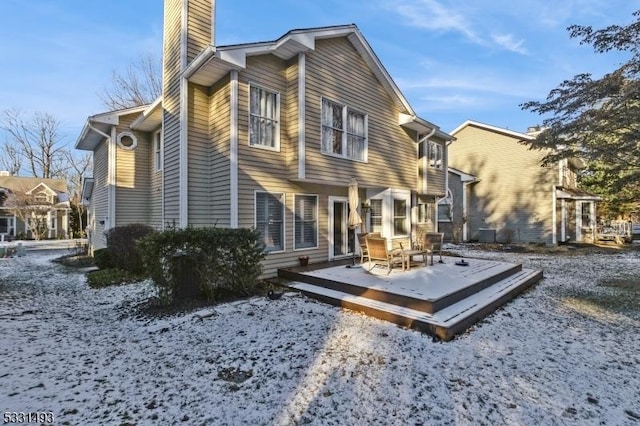 snow covered rear of property featuring a wooden deck