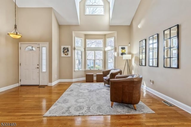 living area with light hardwood / wood-style floors and a high ceiling