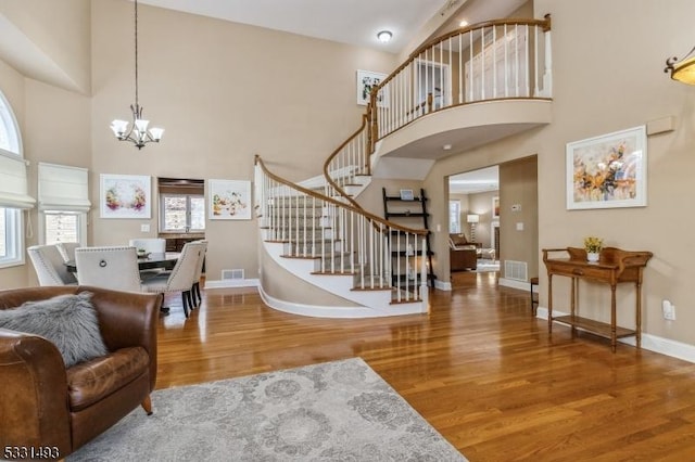 interior space featuring hardwood / wood-style flooring, a notable chandelier, and a towering ceiling