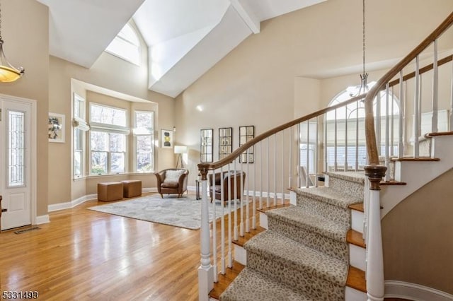 entrance foyer with light hardwood / wood-style flooring, high vaulted ceiling, and a notable chandelier