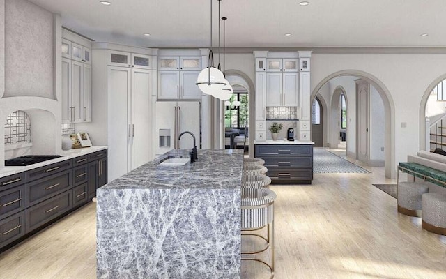 kitchen featuring a center island with sink, black gas stovetop, white cabinetry, and sink