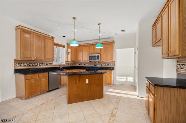 kitchen featuring pendant lighting, sink, stainless steel appliances, a kitchen island, and decorative backsplash