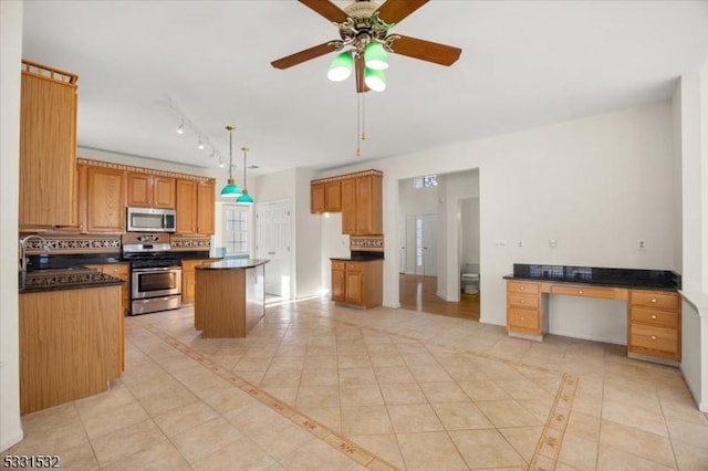 kitchen with sink, light tile patterned floors, a kitchen island, pendant lighting, and stainless steel appliances