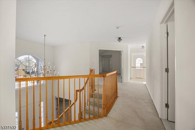 corridor with light colored carpet and a chandelier