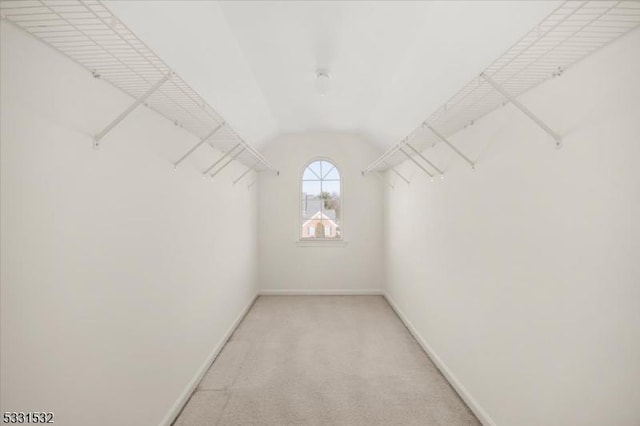 spacious closet with lofted ceiling and light colored carpet