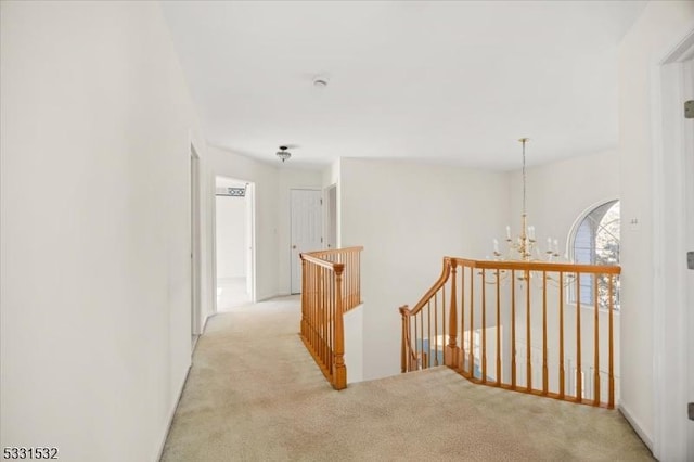 hallway featuring light colored carpet and a notable chandelier