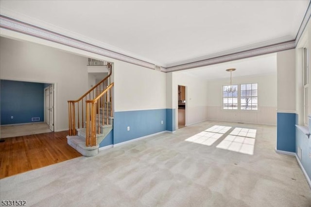 unfurnished living room with a notable chandelier, crown molding, and light colored carpet