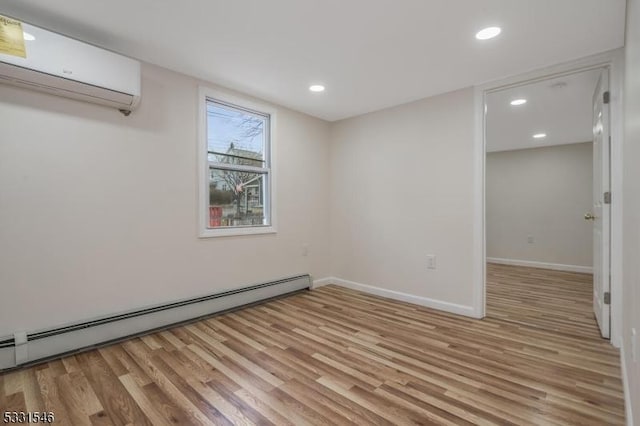 spare room with baseboard heating, a wall unit AC, and light wood-type flooring