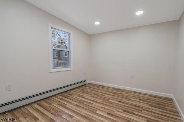 spare room featuring light wood-type flooring and baseboard heating