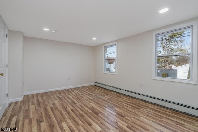 empty room with light wood-type flooring and a baseboard heating unit