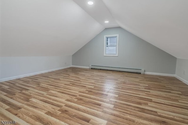 additional living space featuring light hardwood / wood-style floors, vaulted ceiling, and a baseboard radiator