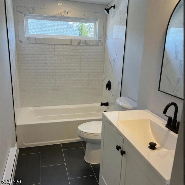 full bathroom featuring tile patterned flooring, vanity, tiled shower / bath combo, and toilet