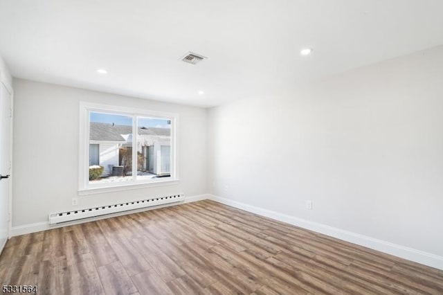 unfurnished room with hardwood / wood-style floors and a baseboard heating unit