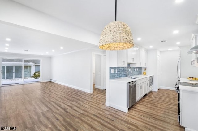 kitchen with tasteful backsplash, stainless steel appliances, sink, decorative light fixtures, and white cabinetry