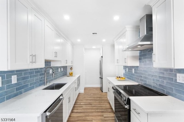 kitchen with wall chimney exhaust hood, white cabinetry, sink, and appliances with stainless steel finishes