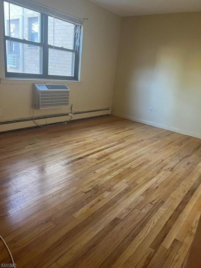 empty room featuring a wall mounted AC, light hardwood / wood-style floors, and a baseboard heating unit