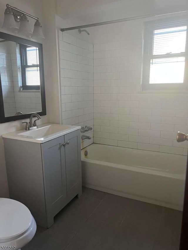 full bathroom with tile patterned floors, vanity, tiled shower / bath combo, and toilet