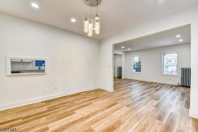 unfurnished living room featuring light hardwood / wood-style flooring and radiator heating unit