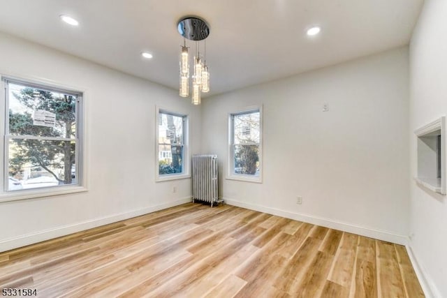 empty room with radiator heating unit and light wood-type flooring