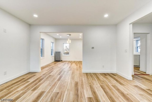 unfurnished living room featuring radiator, plenty of natural light, and light hardwood / wood-style floors