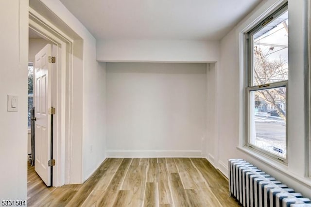 unfurnished room with radiator and light wood-type flooring