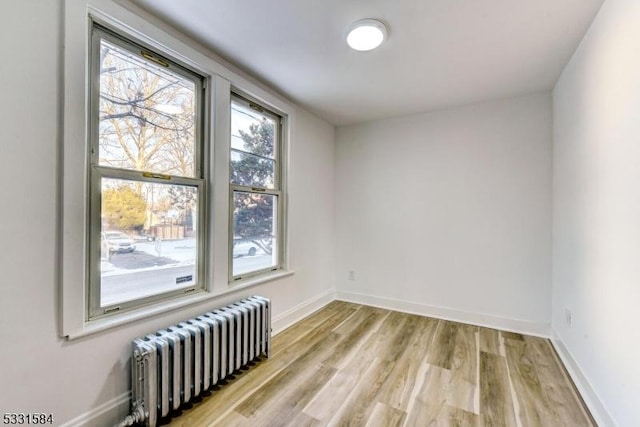 empty room with radiator heating unit and light hardwood / wood-style floors