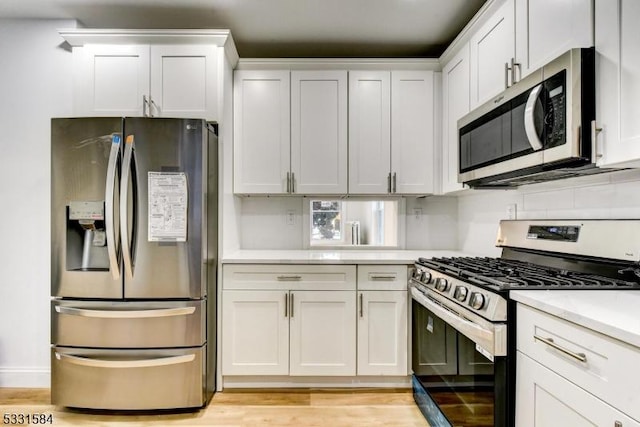 kitchen featuring stainless steel appliances, light hardwood / wood-style floors, and white cabinets