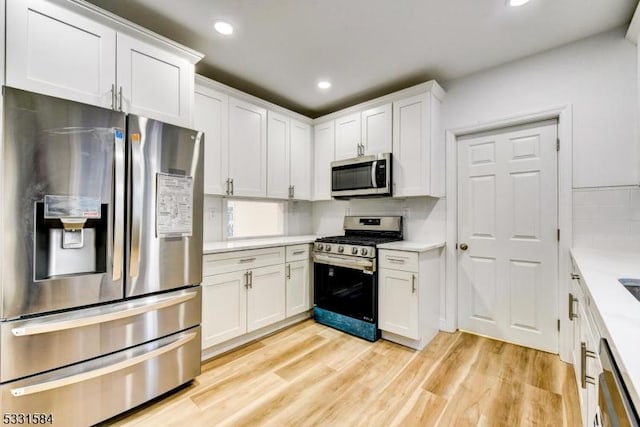 kitchen featuring tasteful backsplash, appliances with stainless steel finishes, white cabinets, and light hardwood / wood-style flooring