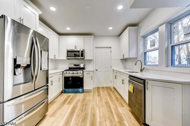 kitchen with sink, stainless steel appliances, light hardwood / wood-style floors, and white cabinets