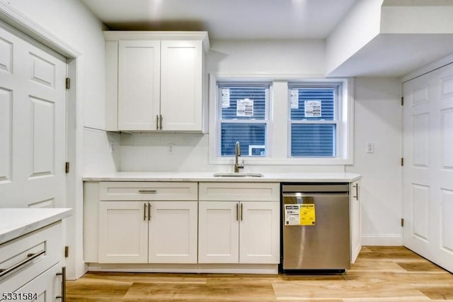 kitchen featuring sink, stainless steel dishwasher, white cabinets, and light wood-type flooring