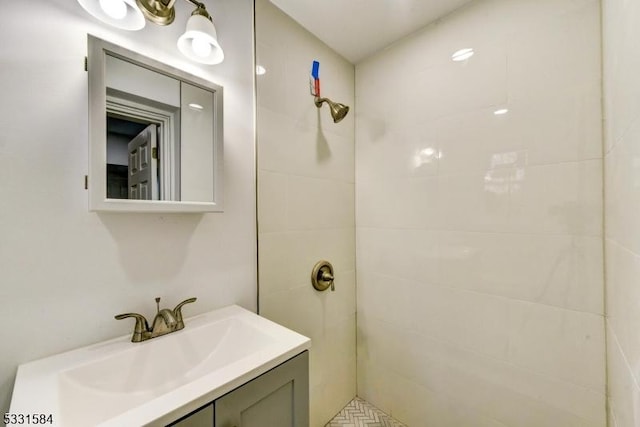 bathroom with tiled shower and vanity